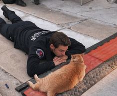 a man laying on the ground next to a cat