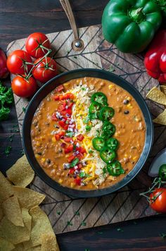 a bowl filled with beans and cheese next to tortilla chips on a cutting board