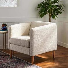 a white chair sitting on top of a wooden floor next to a potted plant