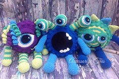 three crocheted stuffed animals sitting next to each other on a wooden surface with wood planks