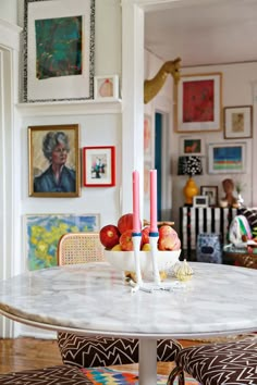 a dining room table with two candles on top of it and some fruit in the middle