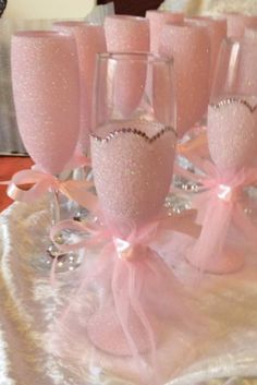 there are many wine glasses with pink bows on the tablecloth and one is empty