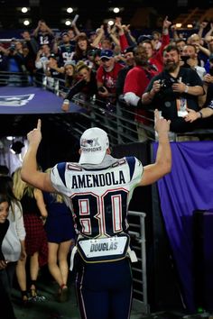 a football player is in the stands with his hands up and people are standing behind him