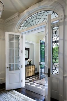 an open door leading to a foyer with a checkered rug and chandelier