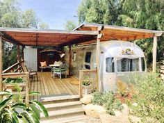 an airstream sits in the middle of a wooded area with steps leading up to it