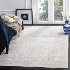 a living room with a blue couch and white rug on the floor next to a window