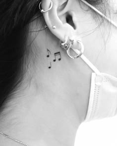 a woman's ear with musical notes on it and a treble behind her ear