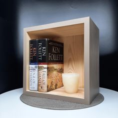 three books in a wooden box on a white table with a candle and two candles