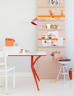 an orange and white desk in a room with shelving on the wall behind it