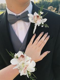 a man in a tuxedo with flowers on his lapel and the bride's hand