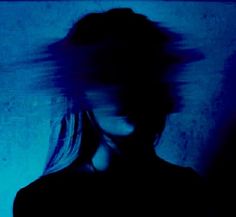 a blurry photo of a woman's face and hair in the dark blue light