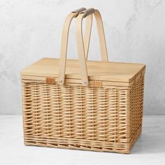 a wicker picnic basket with handles on a white background, showing the top handle