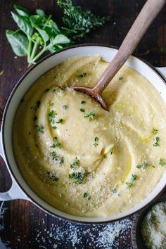 a bowl filled with mashed potatoes and parsley on top of a wooden table