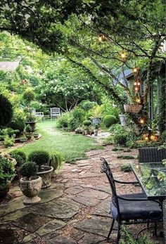 an outdoor dining table and chairs in the middle of a garden with lots of greenery