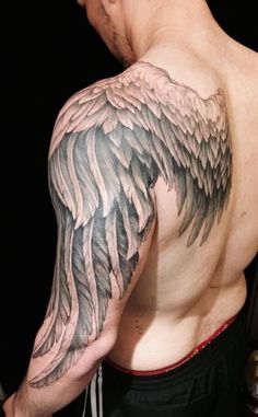 a man with an angel wing tattoo on his arm and shoulder is looking at the camera