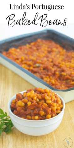 a white bowl filled with baked beans next to a baking pan full of baked beans