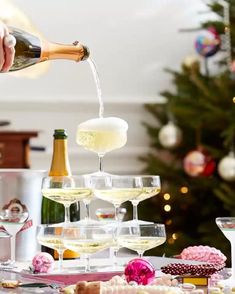 champagne being poured into wine glasses in front of a christmas tree and other holiday decorations