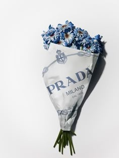 a bouquet of daisies wrapped in paper with the word prada printed on it