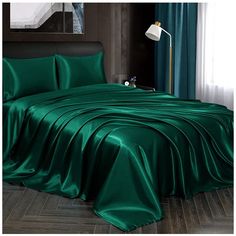 a bed covered in green sheets and pillows