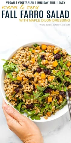 a white bowl filled with farro salad on top of a marble counter next to a hand holding a fork