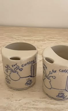 two ceramic cups sitting on top of a wooden table