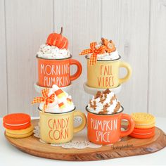 three mugs filled with whipped cream and pumpkin spice sitting on top of a wooden tray