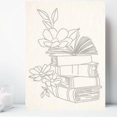 a stack of books sitting on top of a table next to a vase filled with flowers