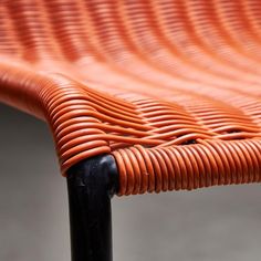 an orange wicker bench with black metal legs