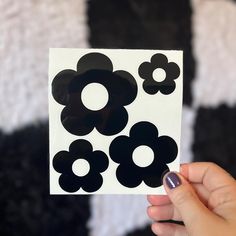 a person holding up a black and white flower sticker