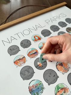 a person's hand is pointing at the national parks sticker on a poster