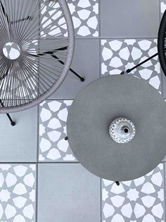 two chairs sitting next to each other on top of a tiled floor with white and gray tiles