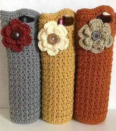 three crocheted vases with flowers are lined up in a row on a table