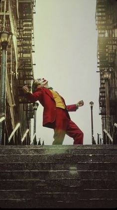 a man in a red suit is walking down some stairs with his arms outstretched and hands out