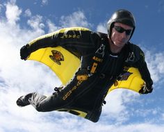 a man flying through the air on top of a snow covered ski slope in front of a blue sky