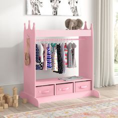 a white shelf with pink bins and clothes hanging on the wall next to it