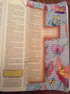 an open bible with butterflies on it and the letter f in the bottom right corner