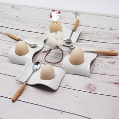 four eggs are placed in the shape of utensils on a white wooden table