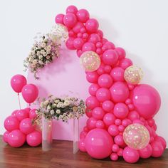 balloons and flowers are arranged on the floor in front of a white wall with pink walls