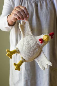 a woman holding a knitted chicken ornament in her hands and wearing a white dress