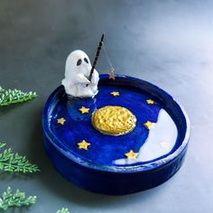 a blue plate with a gold cookie on it and a white ghost holding a stick