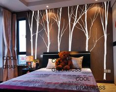 a bed room with a neatly made bed and trees on the wall