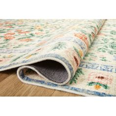 an area rug with multicolored flowers and leaves on the bottom, laying on top of a wooden floor