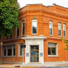 an old brick building on the corner of a street with trees in front of it