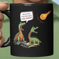 a person holding a black coffee mug with an image of two dinosaurs talking to each other