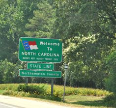 a welcome sign to north carolina on the side of a road with trees in the background