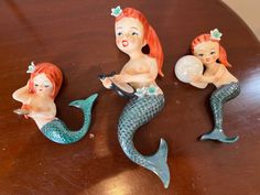 three little mermaid figurines sitting on top of a table