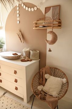 a white dresser sitting next to a chair and a table with a bowl on top of it