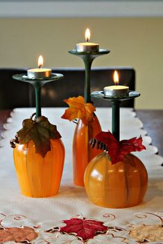 three pumpkins are sitting on a table with candles