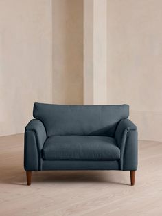 a blue couch sitting on top of a hard wood floor next to a white wall