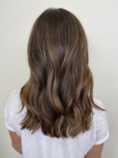 the back of a woman's head with long, wavy hair and brown highlights